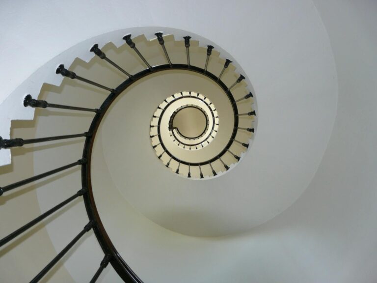 Elegant spiral staircase captured from above, showcasing architectural design and symmetry.